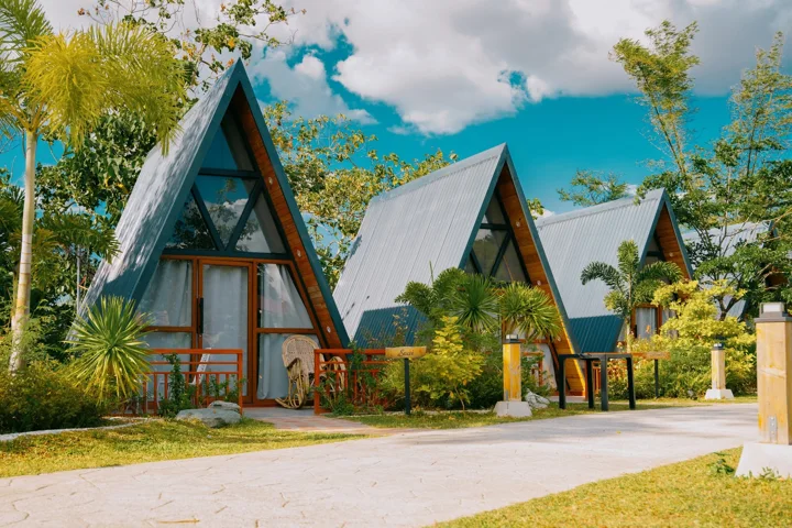 Silver-roofed A-frame cabins with timber porches beneath a blue sky