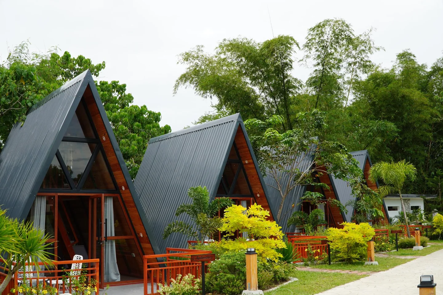 Warm wooden A-frame cabins tucked into the lush gardens at Lucas and Lily’s Farmhouse
