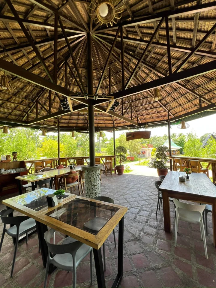 Open-air gazebo dining with wooden tables and a woven roof